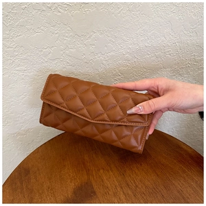 Close-up of brown quilted leather long wallet with elegant envelope flap closure