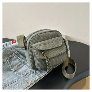 Detail of green corduroy crossbody bag with adjustable strap and woven rope zipper pull