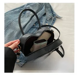 Interior view of heart-shaped black leather bag showing capacity for phone and wallet