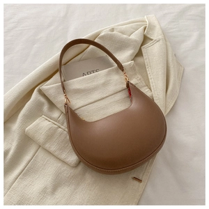 Detail of coffee PU hobo bag with gold hardware on minimalist beige blazer background