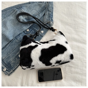 Detail of plush cow print underarm bag with black leather strap and gold hardware