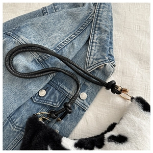Detailed macro view of black and white cow print plush fur texture with golden hardware