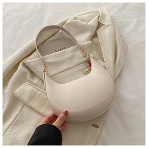 Detail of minimalist cream PU moon bag on beige blazer with golden metal buckle