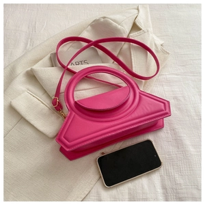 Detailed top view of a hot pink crossbody bag with rounded handle and beige blazer