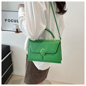 Détail d'un sac à main en similicuir vert avec boucle dorée porté par un mannequin