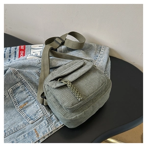 Detail of olive green corduroy crossbody bag texture and adjustable strap on denim