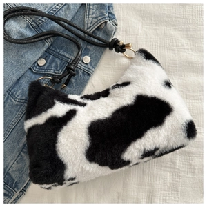 Close-up of plush cow print faux fur underarm bag with black woven strap and gold rings