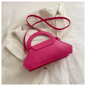 Detail of magenta geometric trapezoid bag with curved handle and adjustable shoulder strap