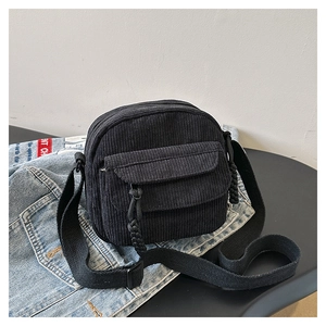 Detail shot of black corduroy crossbody bag with adjustable strap and textured fabric