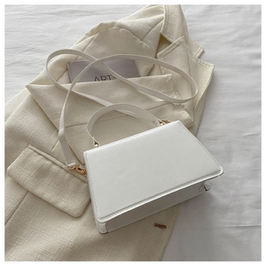 Detail of a white square handbag featuring gold metal hardware and textured PU leather