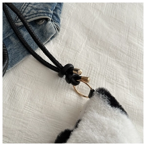 Close-up of the golden metal ring and black drawstring on a plush panda-style bag