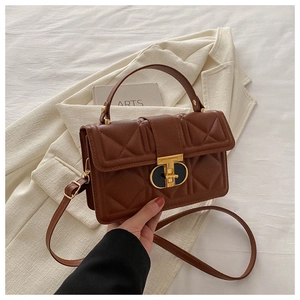 Detail of a brown quilted crossbody bag with a distinctive geometric metal twist lock