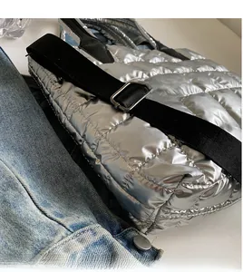 Detail of silver quilted tote bag featuring adjustable black fabric strap and metal buckle