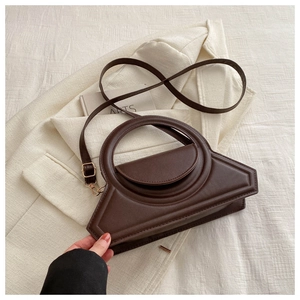Detail of a vintage dark brown matte leather bag on a beige blazer background