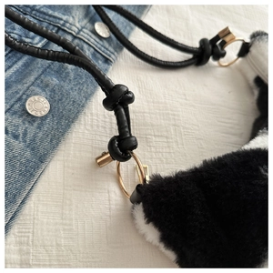 Detail shot of plush black and white faux fur texture with black leather strap and metal ring