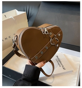 Détail du sac bandoulière en forme de cœur avec rivets en métal et boucles de cœur