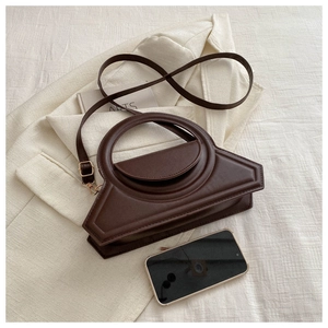 Close-up of dark brown PU leather geometric handbag with unique round cutout handle