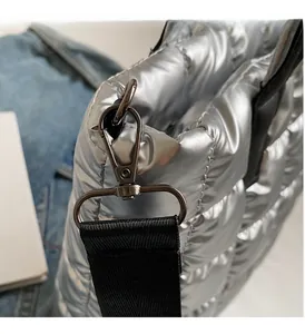 Detailed close-up of gunmetal lobster clasp and D-ring on silver quilted tote bag