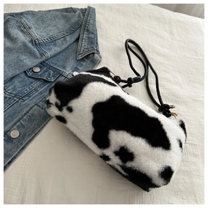 Detail of plush cow print shoulder bag with soft texture and black cord strap