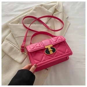 Detail of pink quilted handbag with golden T-bar twist lock on a white fabric background