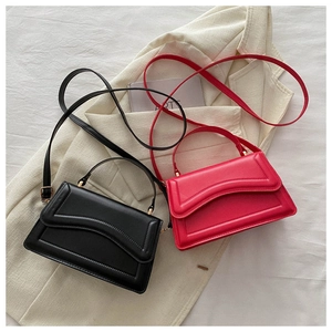 Detail of elegant black and red leather handbags with gold hardware and top handles