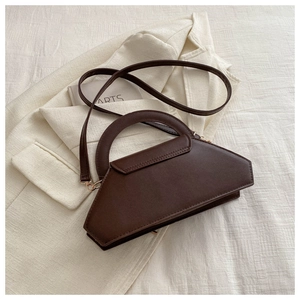 Detail view of a dark brown geometric trapezoid handbag with premium matte leather texture