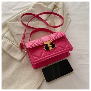 Detailed view of magenta quilted handbag with gold clasp and phone for size reference