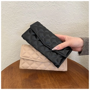 Detailed view of black and beige quilted rectangular purses on a dark wooden table