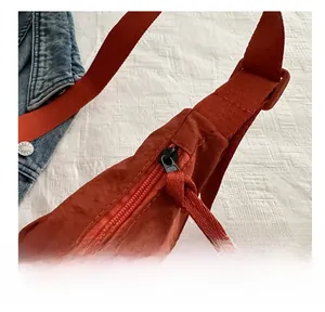 Detail view of the smooth orange-red zipper and woven puller on the casual tote bag