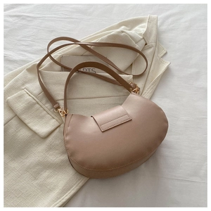 Detail of light brown crescent underarm bag with smooth leather and gold hardware