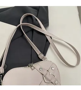 Détail du sac coeur en cuir beige avec boucle métallique et bandoulière ajustable