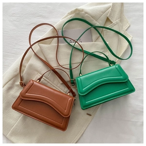 Detailed view of green and brown minimalist handbags with gold hardware and top handles