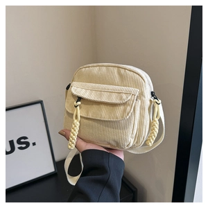 Detailed macro view of beige corduroy shoulder bag with front pocket and zip cord