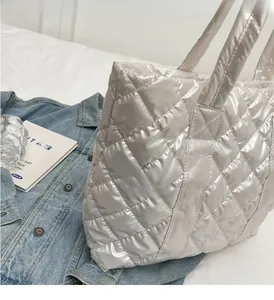 Détail d'un sac cabas argenté matelassé avec une finition brillante et une texture nylon