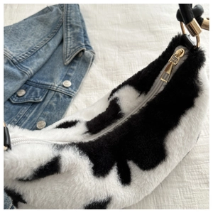 Detail of plush cow print underarm bag with gold zipper and soft faux fur texture