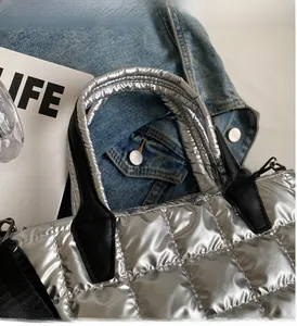 Macro shot of silver quilted tote bag featuring metallic gloss and black handles