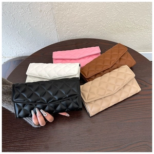Detailed view of quilted envelope clutch bags in multiple colors on a wooden table