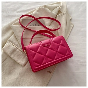 Detail of rose red quilted PU leather handbag with gold buckle on a white blazer