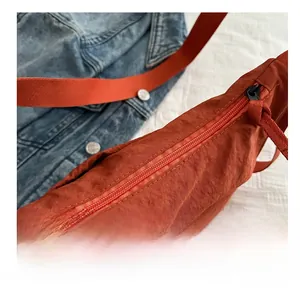Detail view of smooth zipper closure and woven puller on orange nylon tote bag