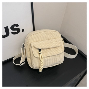 Detail of off-white corduroy crossbody bag texture and adjustable canvas shoulder strap