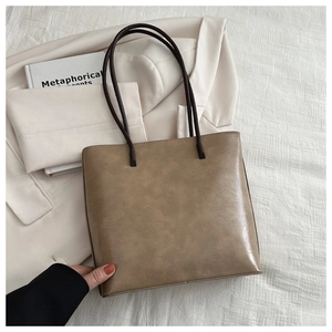Minimalist vintage brown PU leather tote bag displayed with white blazer and books