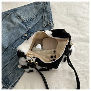 Detail of cow print plush shoulder bag showing spacious interior and golden hardware
