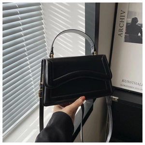 Detail of black faux leather handbag with wave quilting and elegant gold hardware