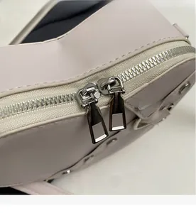 Gros plan détaillé sur les doubles fermetures éclair en métal d'un sac crème en PU
