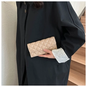 Detail of a beige quilted long clutch bag showing the elegant diamond stitching texture