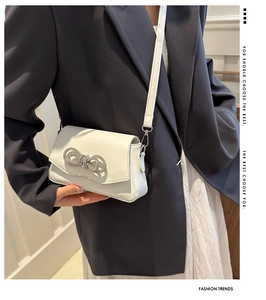 White leather shoulder bag detail with sparkling rhinestone bow and flap closure