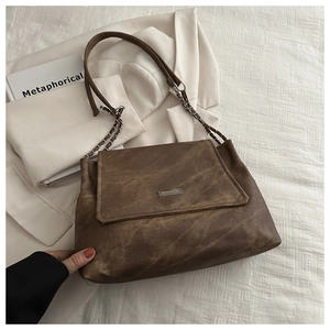 Detail of vintage brown tote bag with metal logo and silver chain leather strap