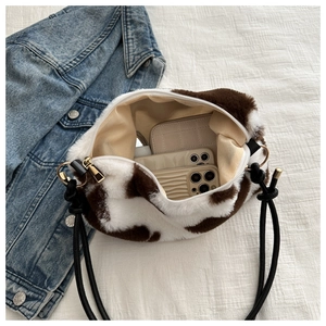 Detail view of large capacity plush cow print shoulder bag with gold hardware and zipper