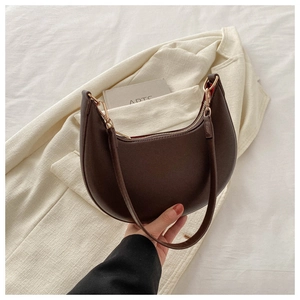 Detail of dark brown crescent underarm bag with gold zipper and leather strap