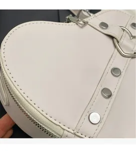 Gros plan d'un sac cœur avec surpiqûres parallèles et détails de rivets en métal argenté